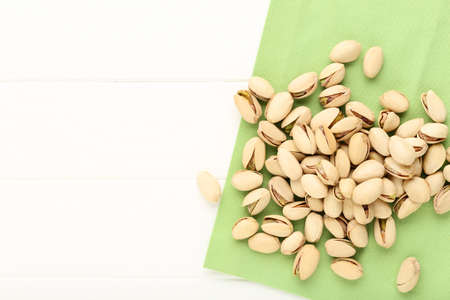 Pistachios with green napkin on white wooden table