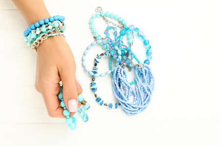 Female hand with blue bracelets on white wooden background