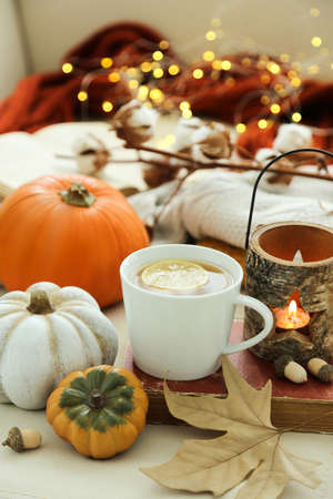 Cup of tea with pumpkins, acorns, dry leaf and candles