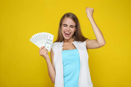 Beautiful woman holding dollar banknotes on yellow background
