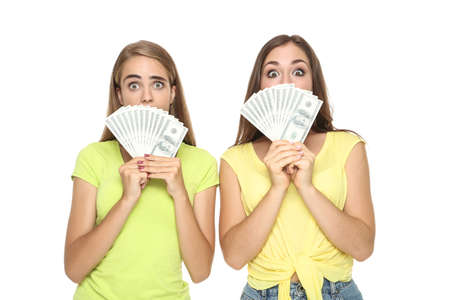 Young happy girlfriends holding dollar banknotes on white backgroundの写真素材