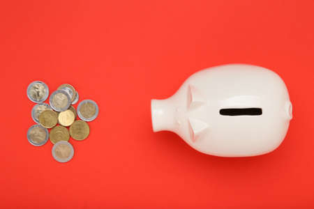 Piggybank with coins on red background