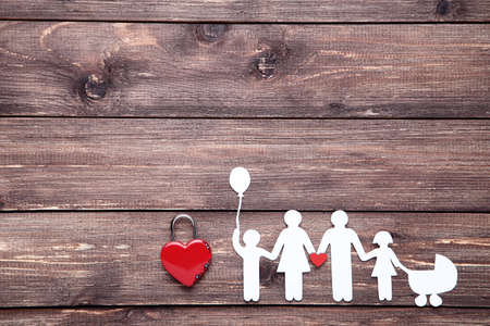 Paper family figures with red padlock heart on brown wooden backgroundの写真素材