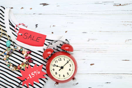 Inscription Sale, striped T-shirt, bracelets and clock on wooden background