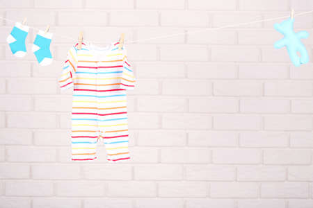 Baby clothes with soft toy hanging on brick wall backgroundの写真素材
