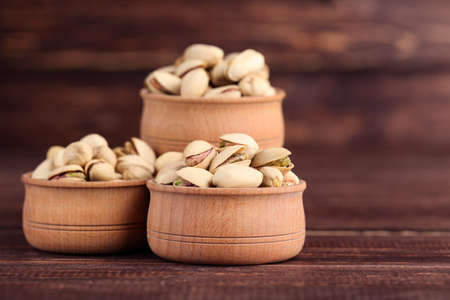 Pistachios in bowls on brown wooden table