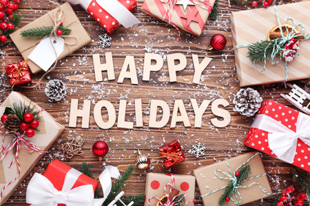 Text Happy Holidays with gift boxes and ornaments on brown wooden backgroundの写真素材