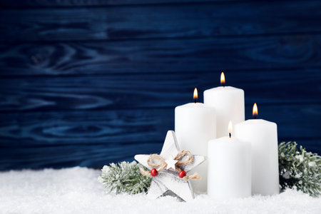 Christmas candles with star and fir tree branches on blue wooden backgroundの写真素材