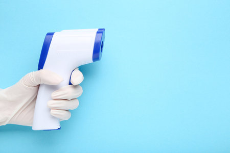 Medical infrared thermometer in doctor hand on blue background