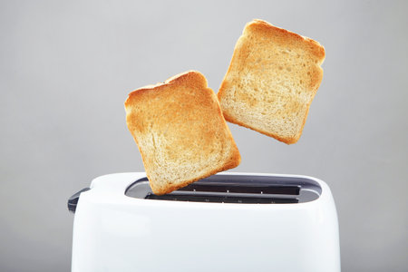 Toasts jumping out of the toaster on gray backgroundの写真素材
