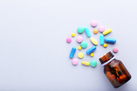 Colorful pills and bottle on gray background