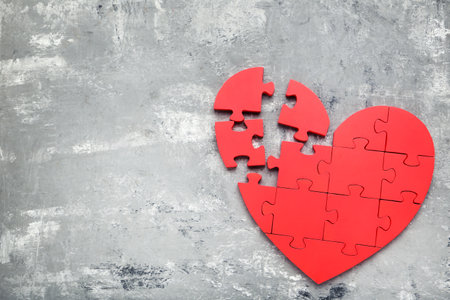 Broken puzzle heart on gray backgroundの写真素材