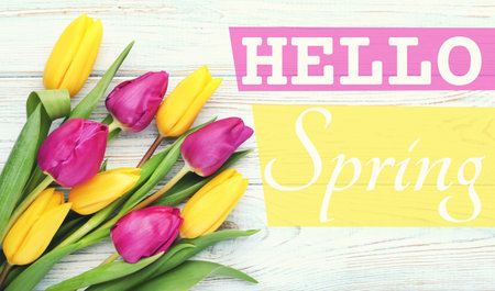 Bouquet of tulips with text Hello Spring on wooden tableの写真素材