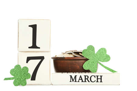St. Patrick's Day. Cube calendar with paper clover leafs and coins isolated on white background