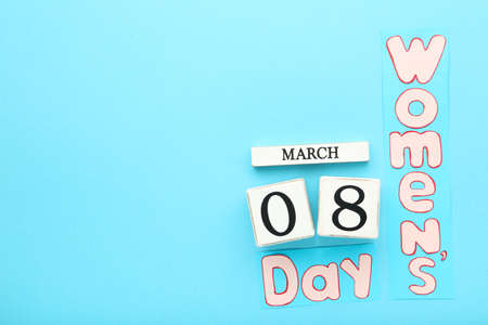 White wooden calendar cubes and inscription Womens Day on blue background