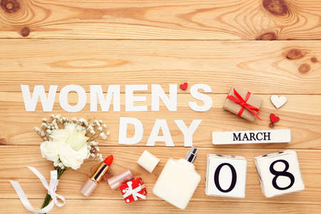 ? alendar cubes, bouquet of flowers, gift boxes, lipstick, perfume bottle and text Womens Day on wooden backgroundの写真素材
