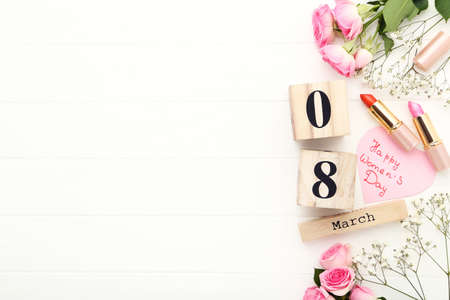 Wooden calendar with text Happy Womens Day, flowers and lipsticks on white backgroundの写真素材