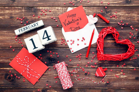 February block calendar with hearts, envelope and text Happy Valentines Day on brown wooden table