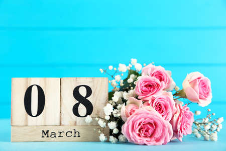 Calendar cubes and bouquet of flowers on blue wooden backgroundの写真素材