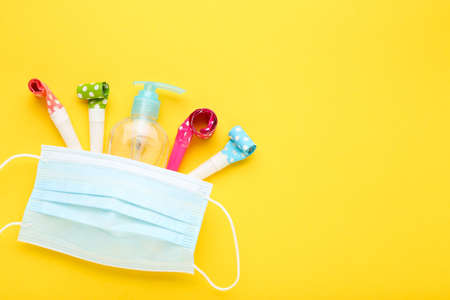 Medical mask with gel sanitizer and whistles on yellow backgroundの写真素材
