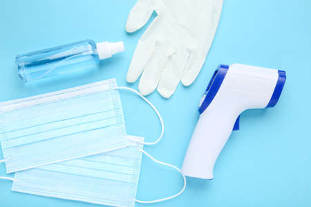 Medical masks, gloves, sanitizer bottle and infrared thermometer on blue backgroundの写真素材