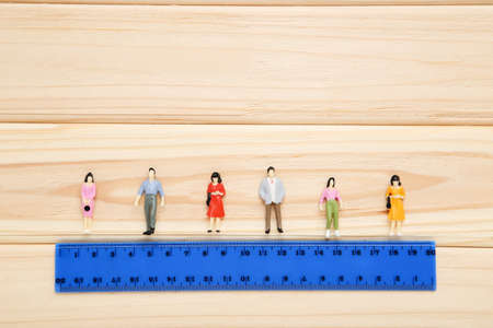 Social distancing. Miniature people with blue ruler on brown wooden backgroundの写真素材