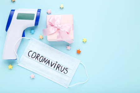 Medical mask and text Coronavirus, infrared thermometer, gift box and paper stars on blue backgroundの写真素材
