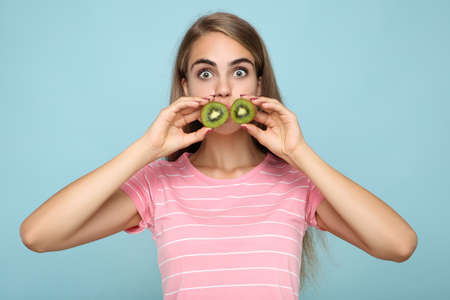 Young girl holding kiwi fruit on blue backgroundの写真素材