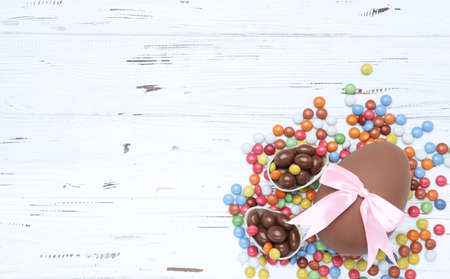 Easter chocolate eggs and candies on white wooden table