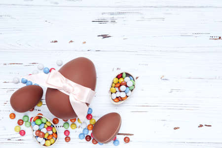 Easter chocolate eggs and candies on white wooden table
