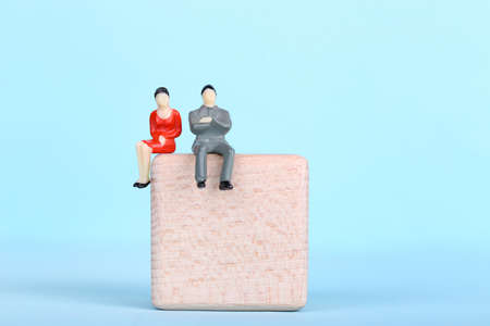 Miniature people with wooden cube on blue backgroundの写真素材