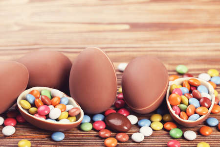 Easter chocolate eggs with candies on brown wooden table