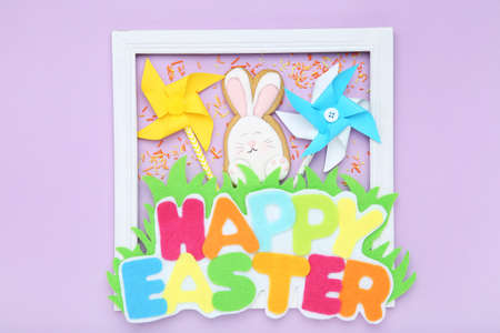 Text Happy Easter with rabbit cookie and paper windmills on purple backgroundの写真素材