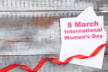 Card with text 8 March International Womens Day in envelope and red ribbon on wooden backgroundの写真素材