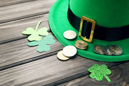 St. Patrick's Day. Paper clover leafs with coins and hat on wooden tableの写真素材