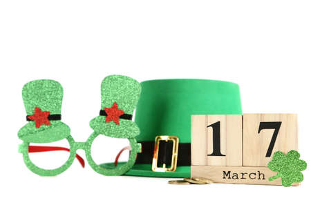 St. Patrick's Day. Eyeglasses with hat, cube calendar and paper clover leaf on white background