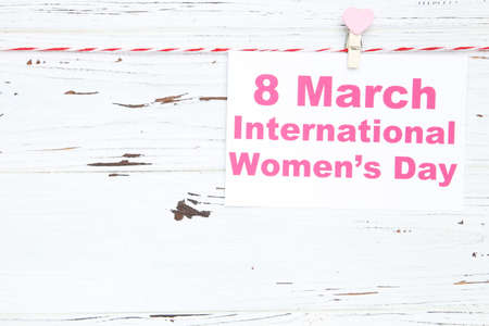 Card with text 8 march International Womens Day hanging on rope on white wooden backgroundの写真素材