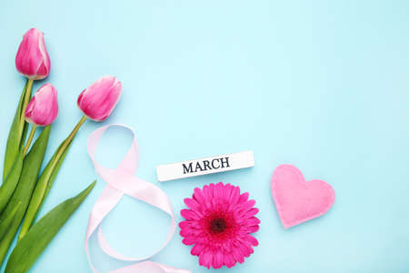 Gerbera and tulip flowers, fabric heart and ribbon in shape of number 8 on blue backgroundの写真素材