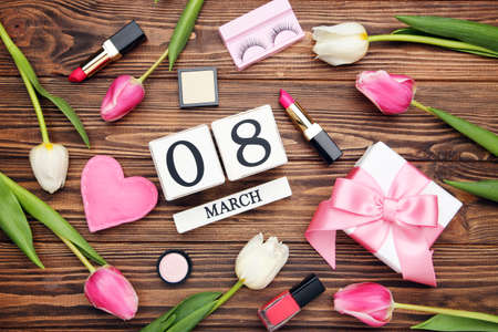 Tulip flowers, gift box, pink fabric heart and cube calendar on brown wooden background