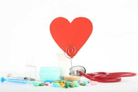 Doctor's Day concept. Red paper heart, stethoscope and colorful pills on white background