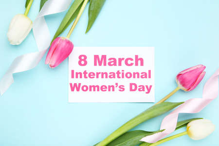 Tulip flowers, ribbons and card with text 8 March International Womens Day on blue backgroundの写真素材
