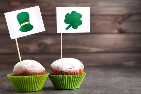Cupcakes and flags with picture of St. Patrick's hat and clover leaf on wooden background