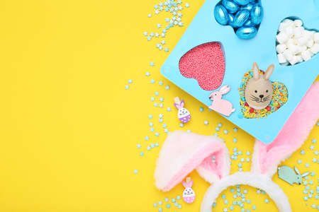 Easter concept. Colorful sprinkles, eggs, marshmallows and rabbit ears on yellow backgroundの写真素材