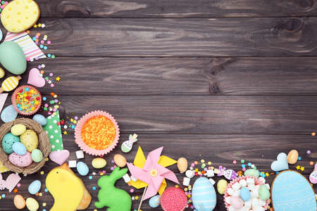 Easter gingerbread cookies with eggs, sprinkles and marshmallows on brown wooden table