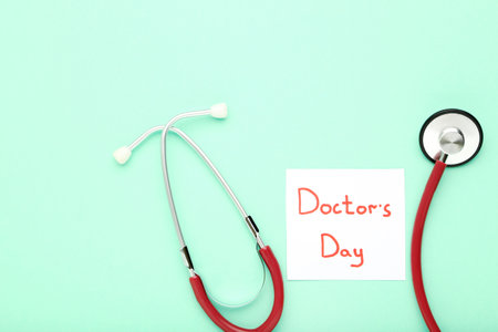 Stethoscope and paper with text Doctor's Day on mint backgroundの写真素材