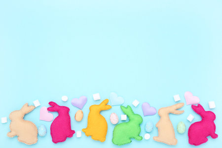 Easter concept. Fabric rabbits with eggs and marshmallows on blue backgroundの写真素材