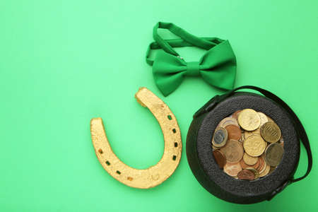 Pot of coins with golden horseshoe and bow tie on green background. Concept St. Patrick's Dayの写真素材