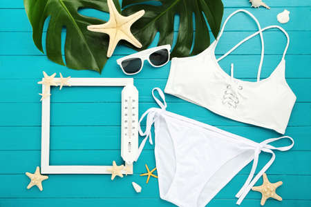 Fashion swimsuit with starfishes, sunglasses and monstera leafs on blue wooden tableの写真素材