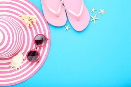 Summer straw hat with sunglasses, flip flops and seashells on blue backgroundの写真素材