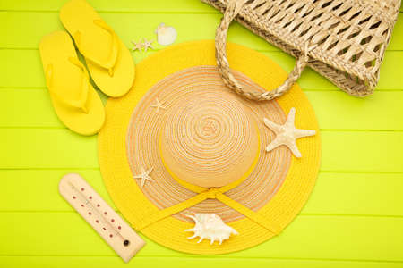 Summer straw hat with flip flops, thermometer, bag and seashells on green wooden tableの写真素材
